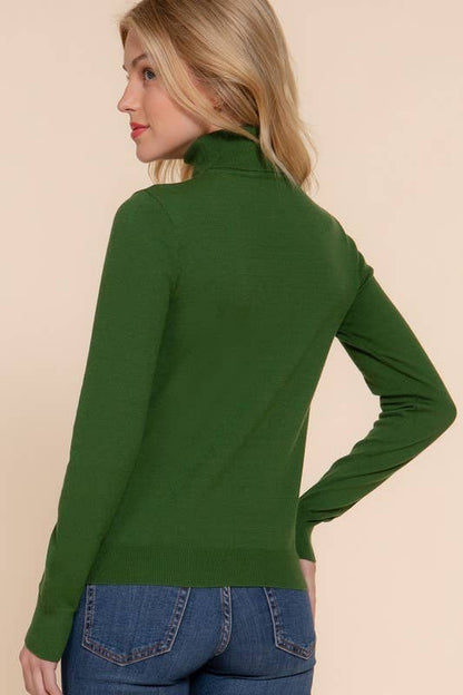 Woman wearing a green sweater and blue jeans on a beige background