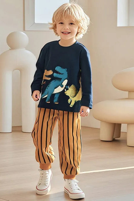 Child wearing a navy sweater with dinosaur design and striped pants in a modern indoor setting