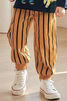 Child wearing a navy sweater with dinosaur designs and striped pants in a modern indoor setting.