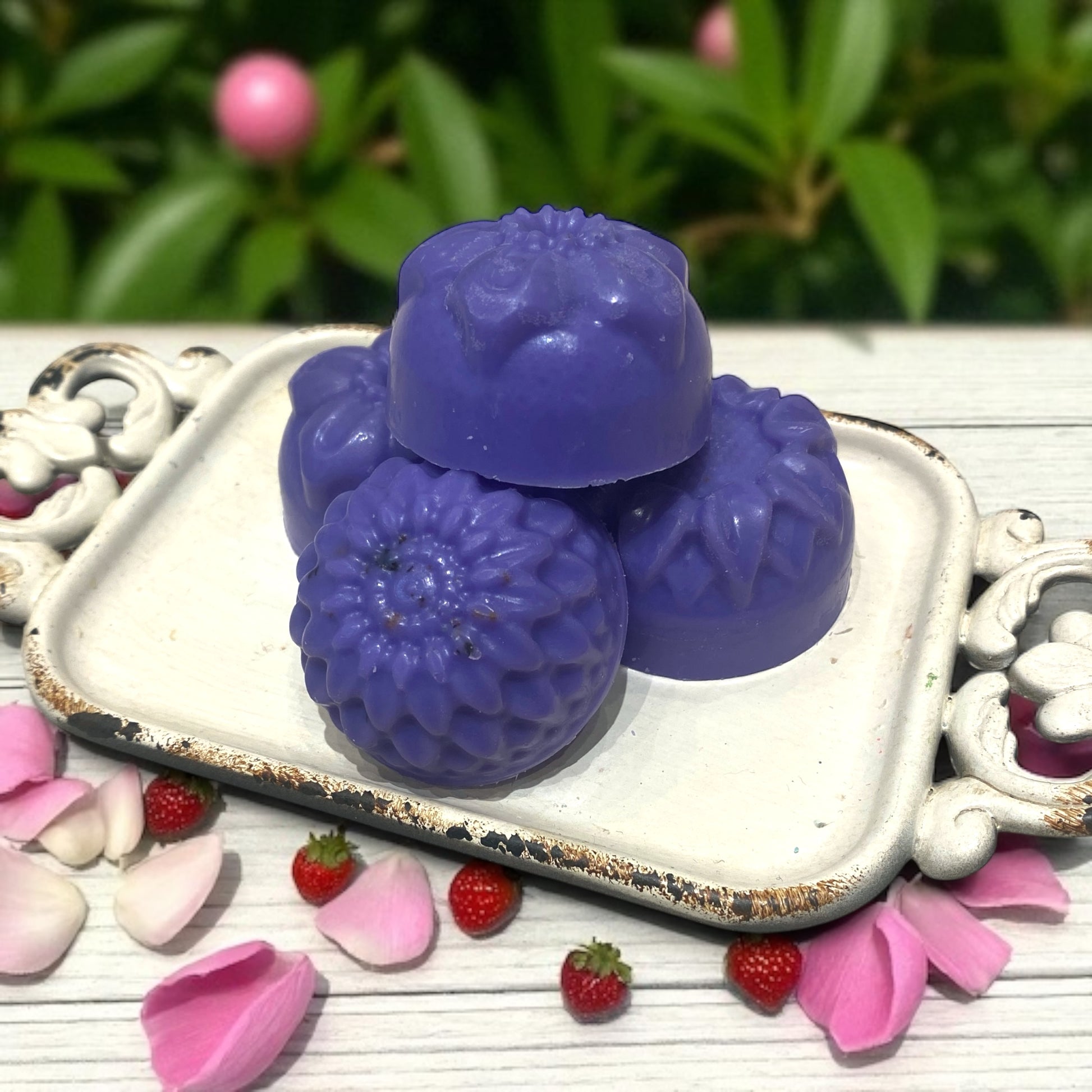 Purple bird-shaped soap on a decorative tray with flowers and berries