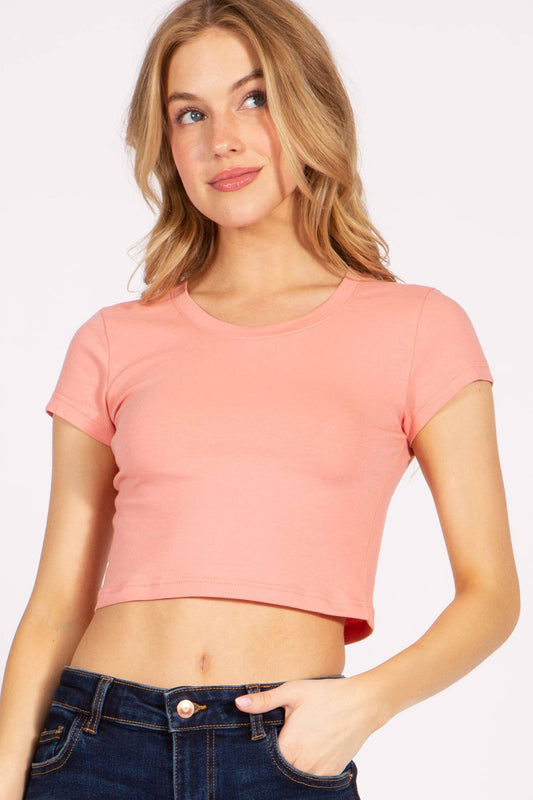 Woman wearing a pink crop top and blue jeans on a white background