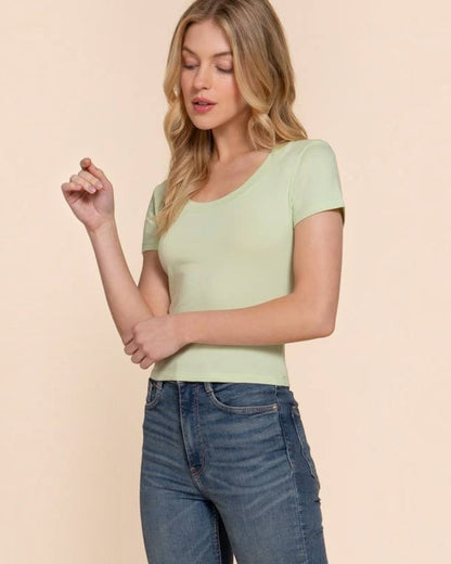 Woman wearing a light green top and blue jeans against a beige background