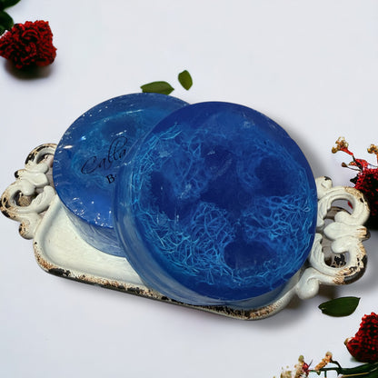 Two blue textured soaps on a decorative white tray with floral elements.