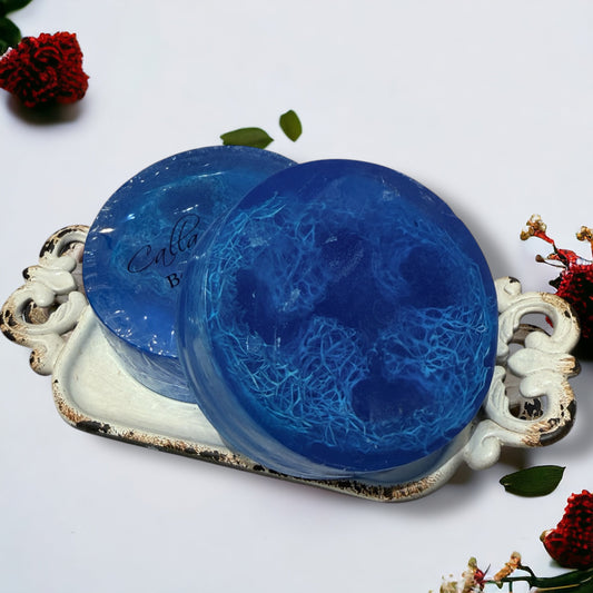 Two blue textured soaps on a decorative white tray with floral elements.