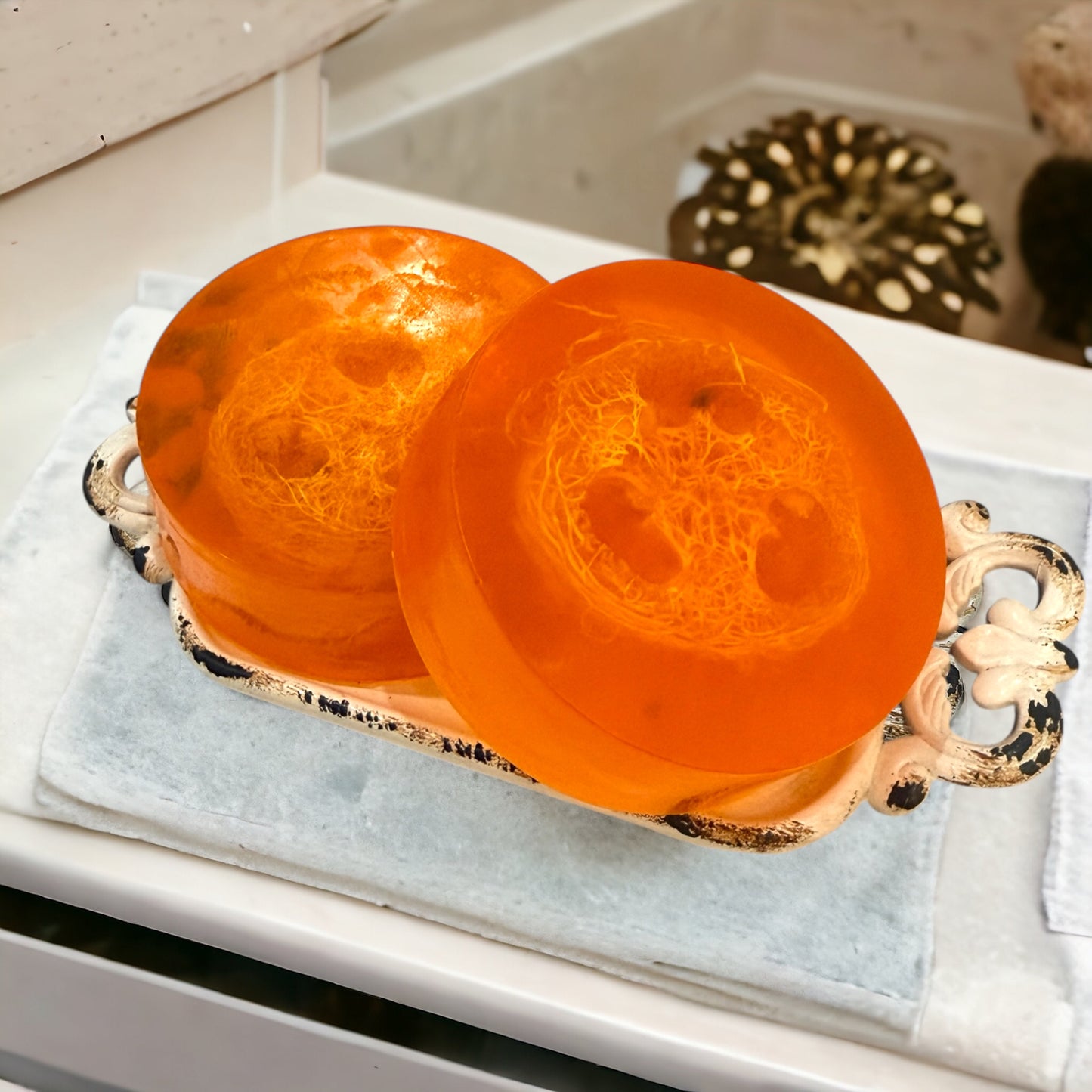 Two orange soap bars on a decorative tray with a blurred background