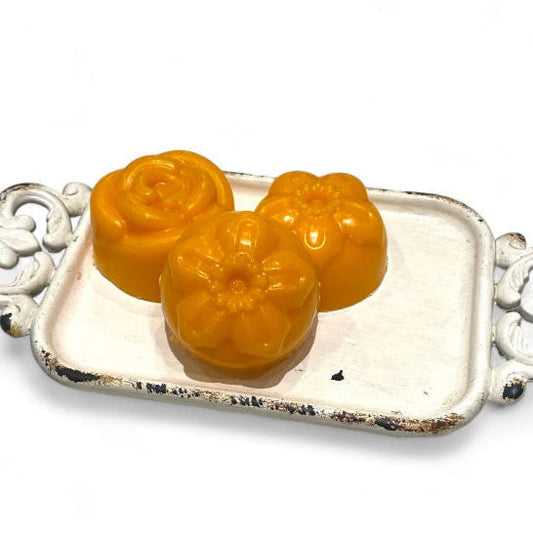 Three yellow floral-shaped objects on a decorative silver tray with a white background