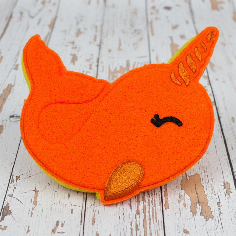 Orange narwhal-shaped object on pebbles