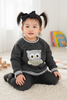 Child wearing a dark gray sweater with an owl design, sitting on a light-colored floor.