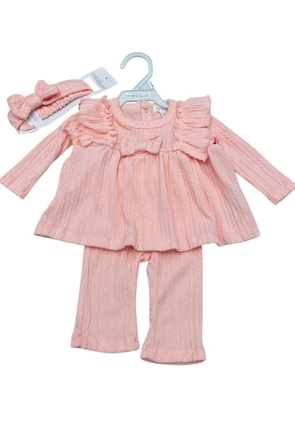 Pink baby outfit with top, pants, and headband on a white background