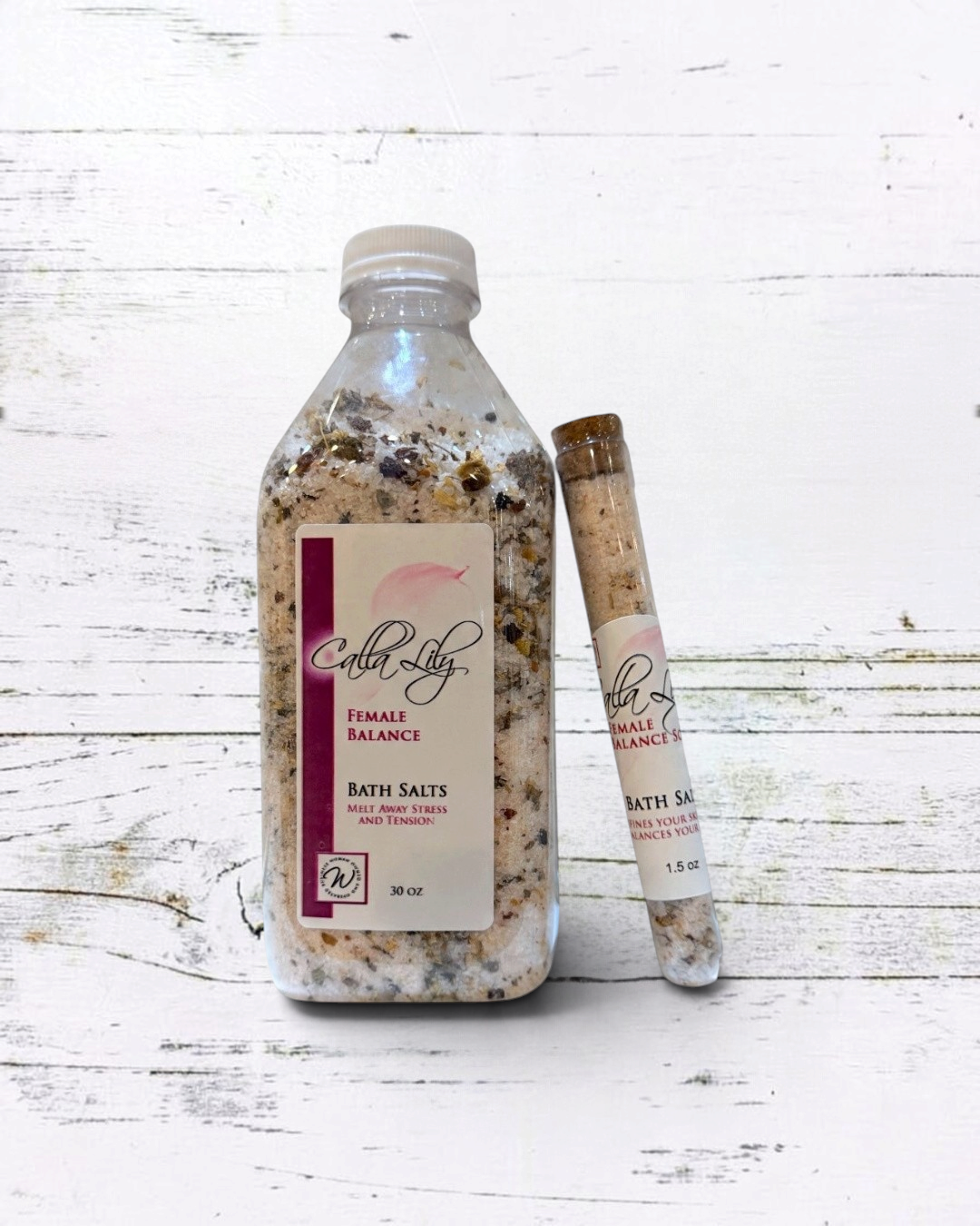 Calla Lily Cosmetics + CL kids Female Balance bath salts in a large bottle and small glass vial with floral botanicals.