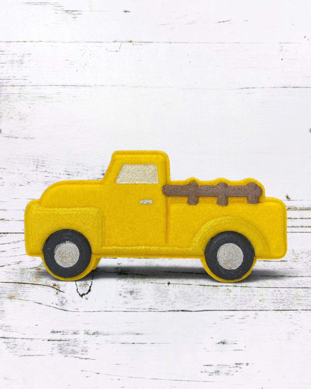 Calla Lily Cosmetics + CL kids yellow vintage truck bath bomb with pineapple scent on a white wooden background