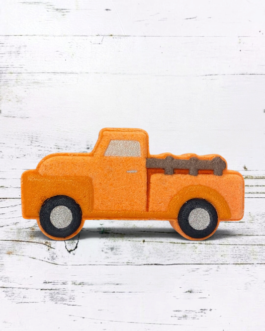 Calla Lily Cosmetics + CL kids orange vintage truck bath bomb with strawberry banana scent on a white wood background