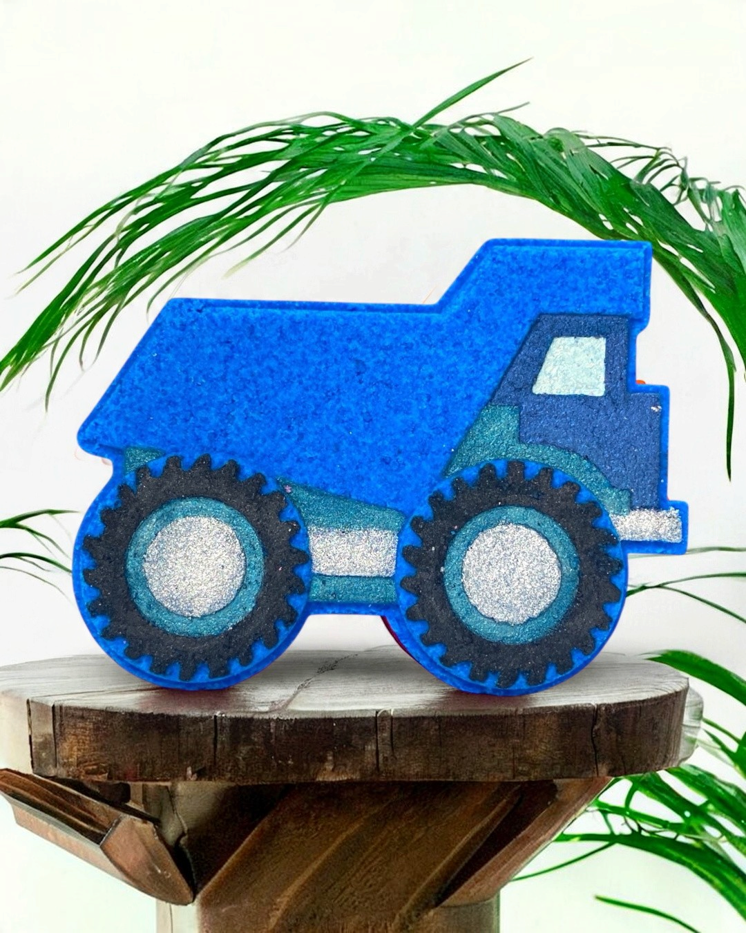 Calla Lily Cosmetics + CL kids blue dump truck shaped bath bomb with blueberry scent on a wooden stand