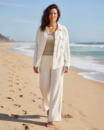 Woman standing on a sandy beach with ocean waves in the background