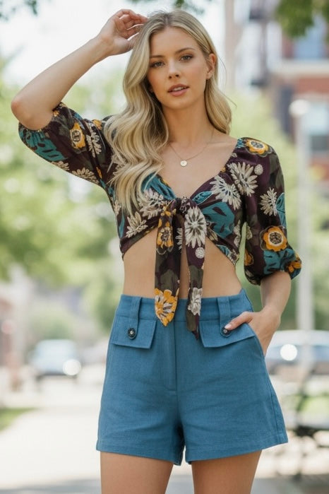 Woman wearing a floral top and blue shorts outdoors