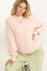 Person wearing a light pink sweater and green pants on a white background