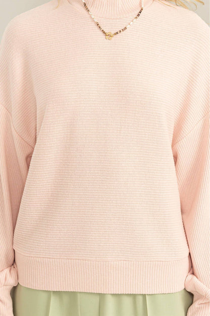 Pink sweater worn by a person on a white background