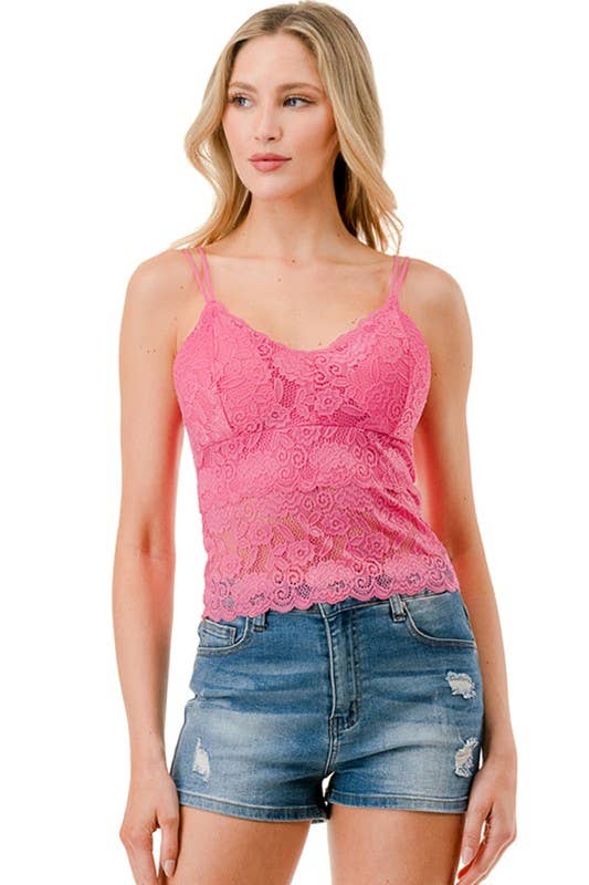 Woman wearing a pink lace tank top and denim shorts on a white background