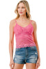 Woman wearing a pink lace tank top and denim shorts on a white background