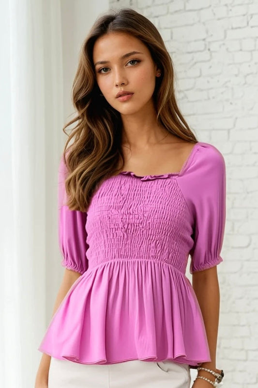 Woman wearing a pink blouse against a white brick wall