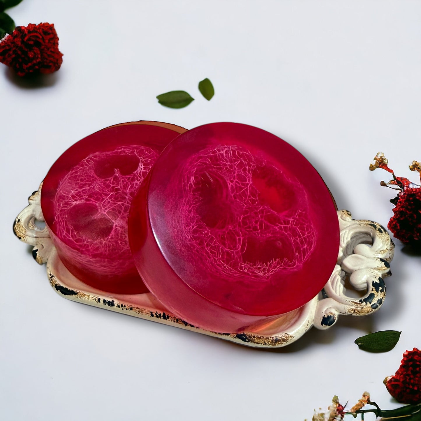 Two pink soaps on a decorative tray with floral elements on a light background