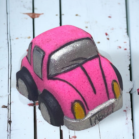 Pink and gray bath bomb car on a white wooden surface