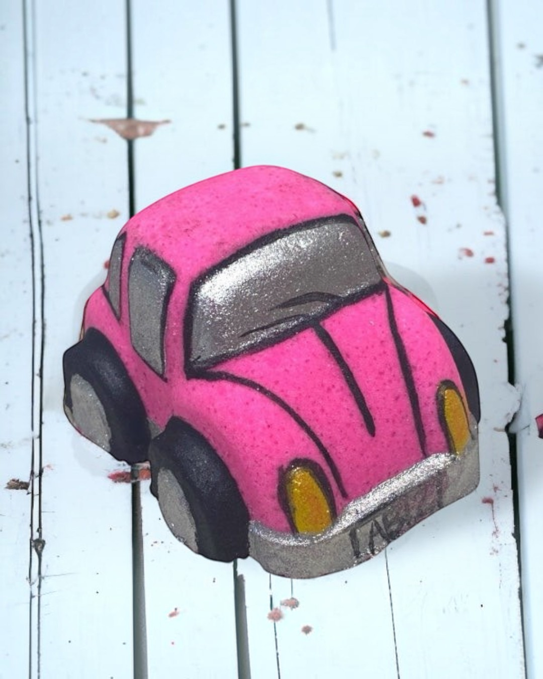 Pink and gray bath bomb car on a white wooden surface