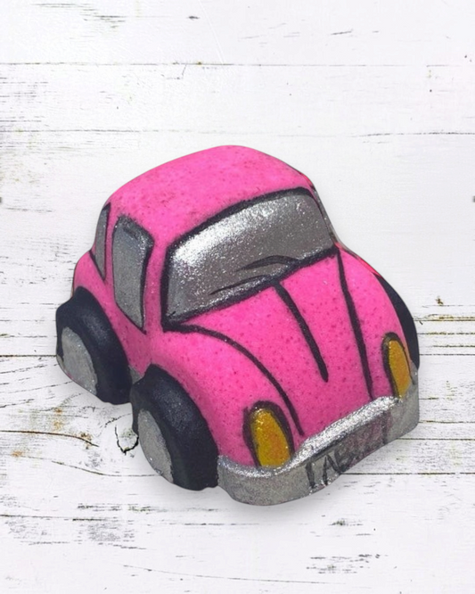 Pink and gray bath bomb car on a white wooden surface