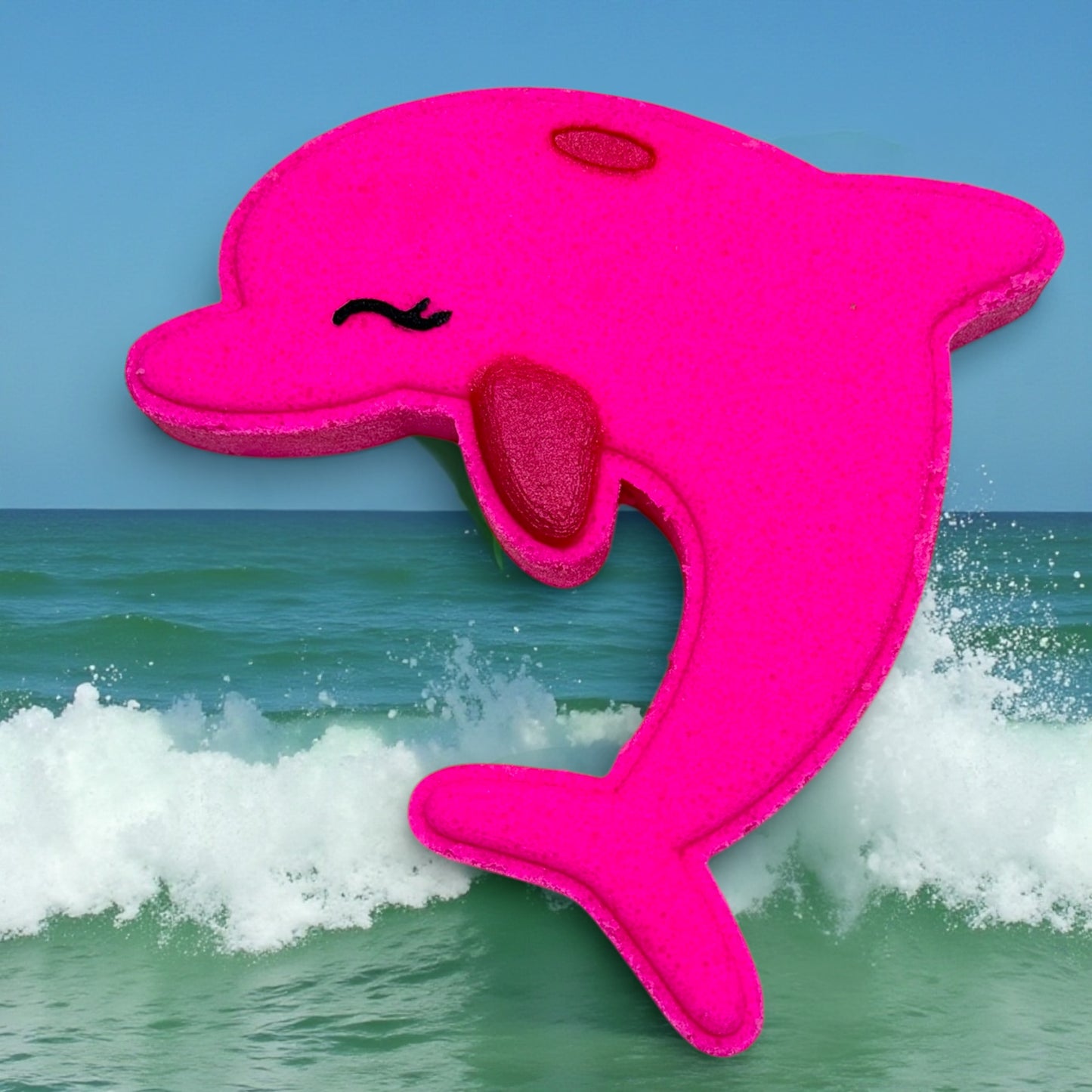 Pink dolphin-shaped bath bomb in front of ocean waves