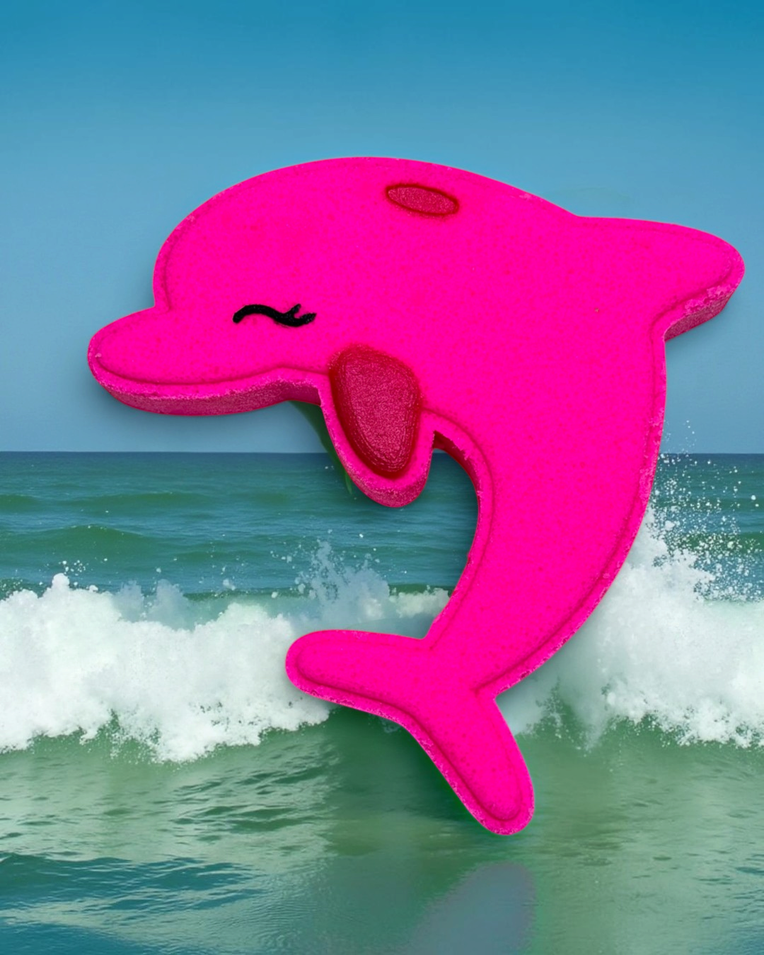 Pink dolphin-shaped bath bomb in front of ocean waves