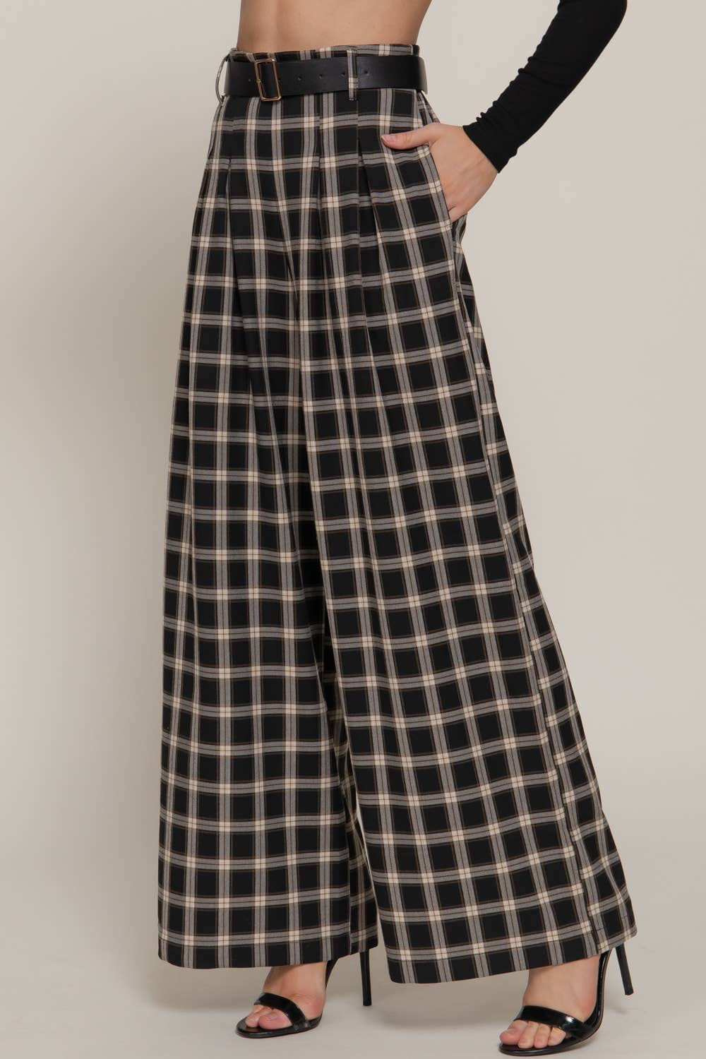 Person wearing black and beige plaid wide-leg pants on a plain background