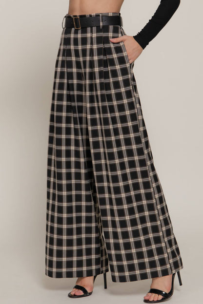 Person wearing black and beige plaid wide-leg pants on a plain background