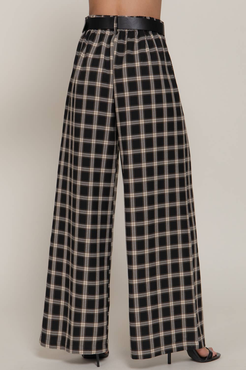 Black and beige plaid pants worn by a person on a plain background