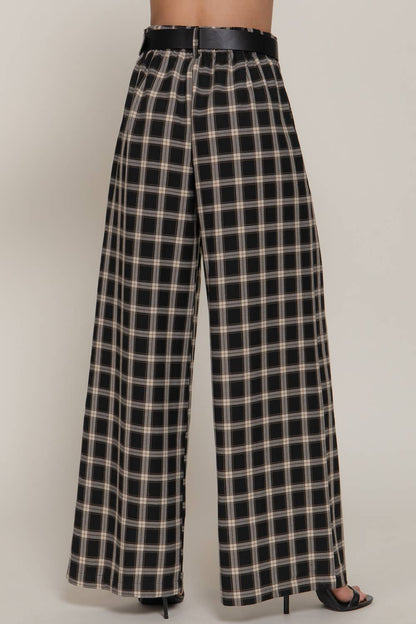 Black and beige plaid pants worn by a person on a plain background