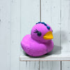 Purple rubber duck with decorative elements on a white wooden surface
