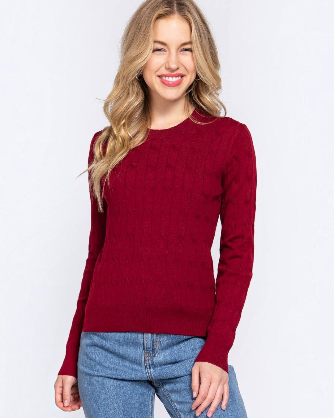 Woman wearing a red sweater and blue jeans on a white background