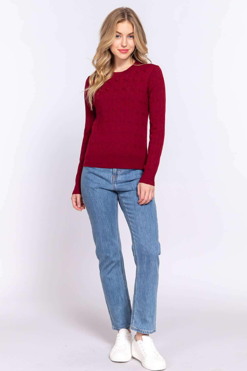 Woman wearing a red sweater and blue jeans on a white background