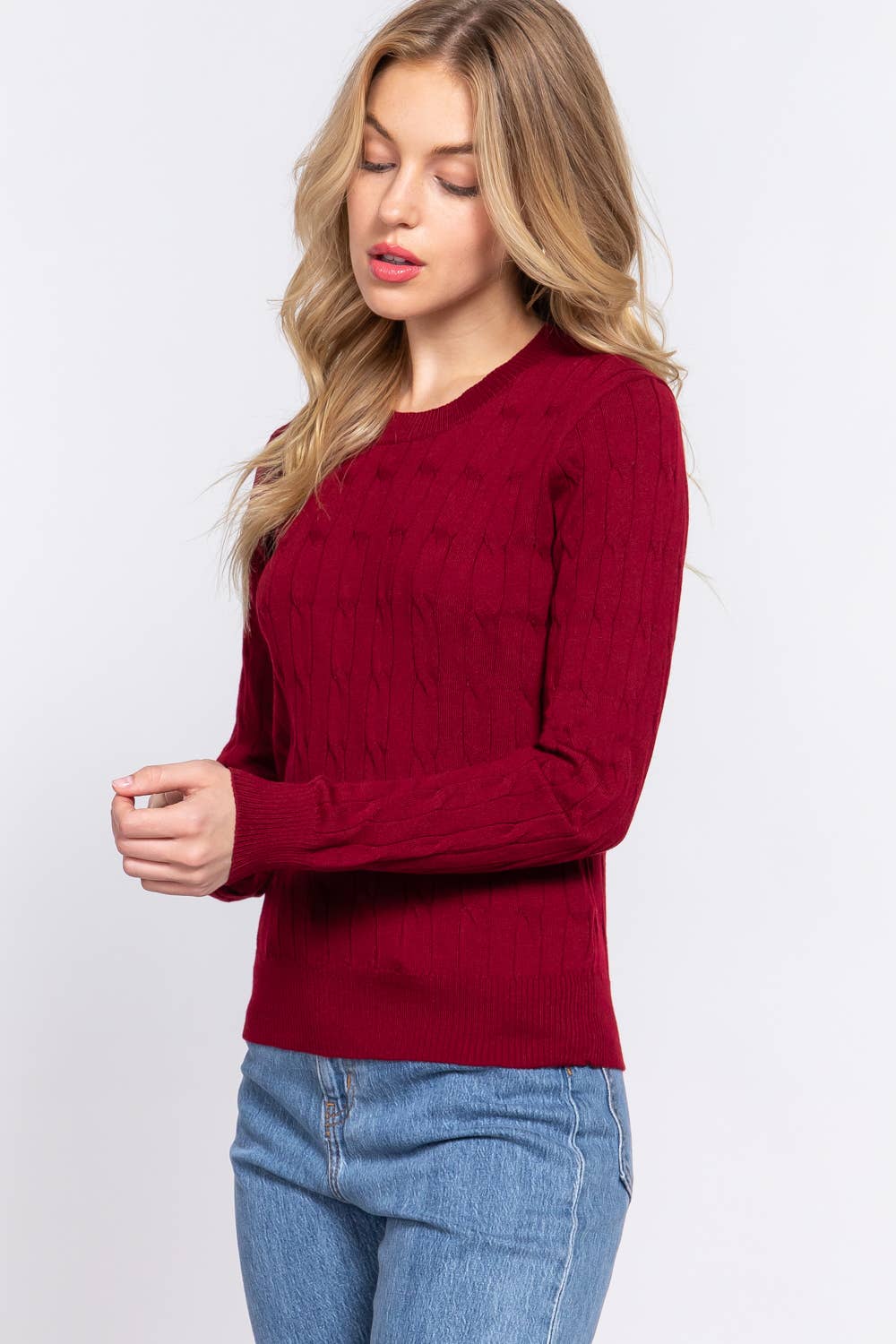 Woman wearing a red sweater and blue jeans on a white background