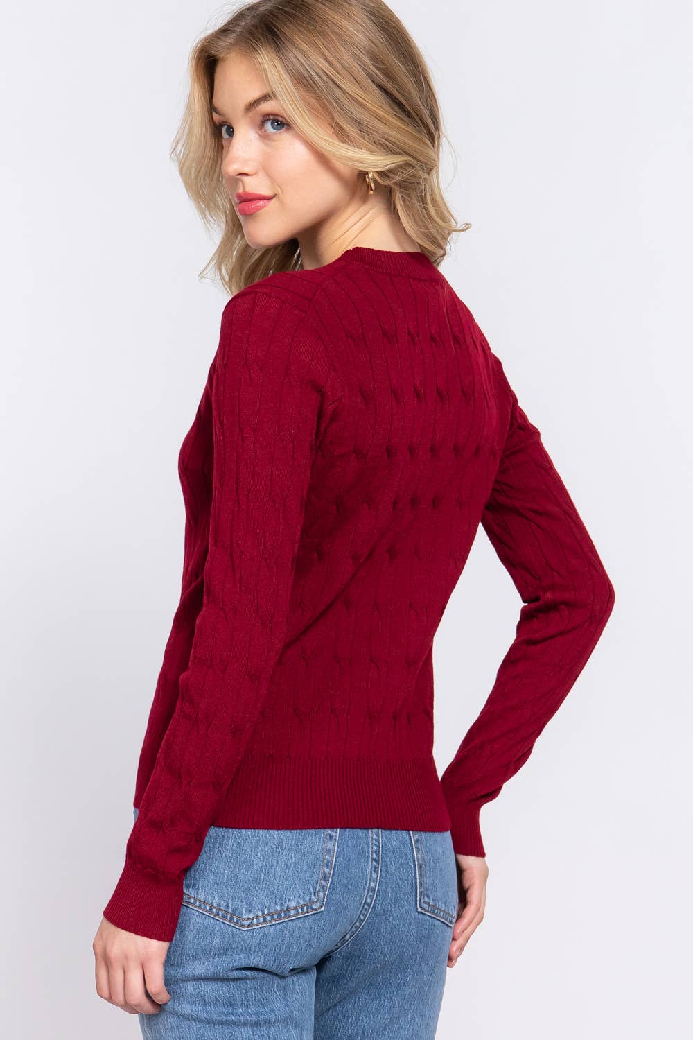 Woman wearing a red sweater and blue jeans on a white background