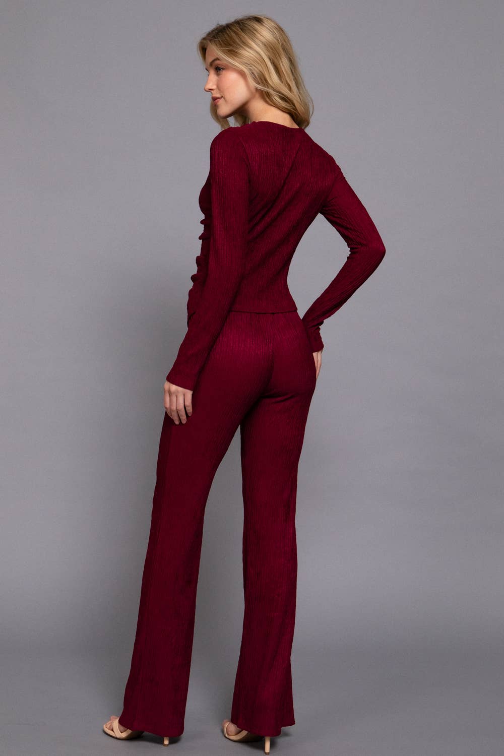 Woman wearing a burgundy jumpsuit against a gray background