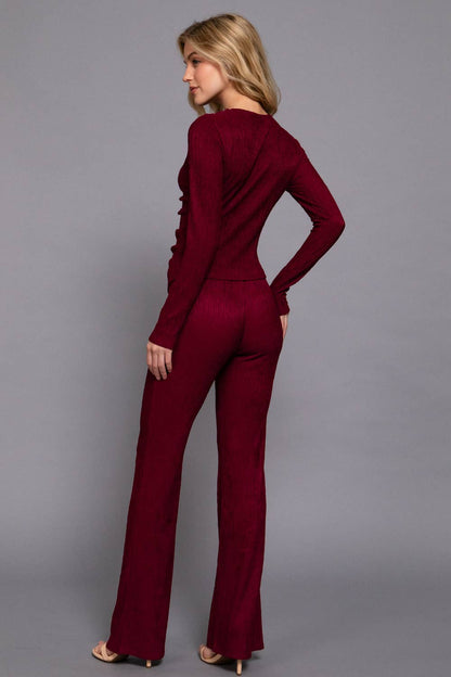 Woman wearing a burgundy jumpsuit against a gray background