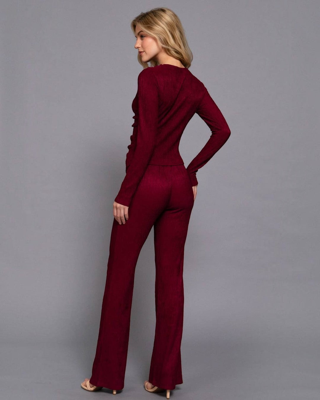 Woman wearing a burgundy jumpsuit against a gray background