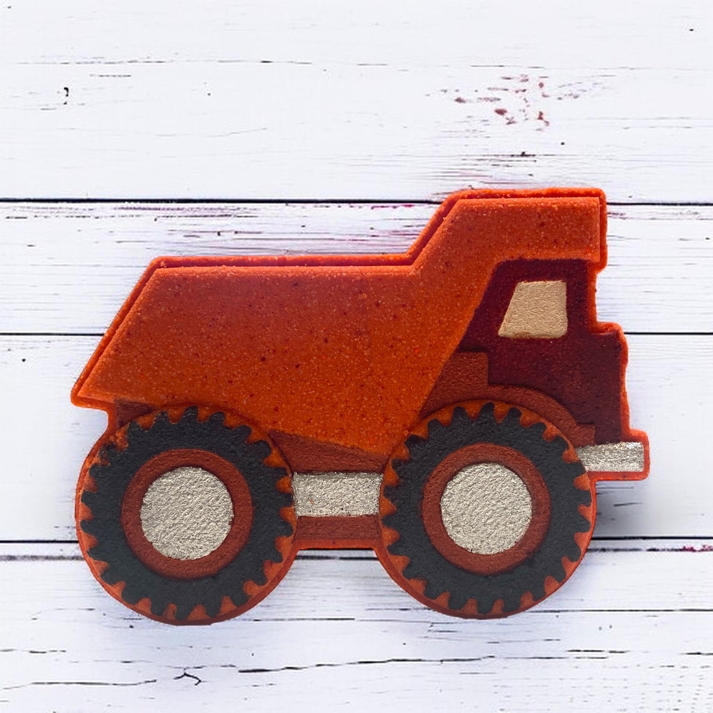 Red bath bomb dump truck on a white wooden surface