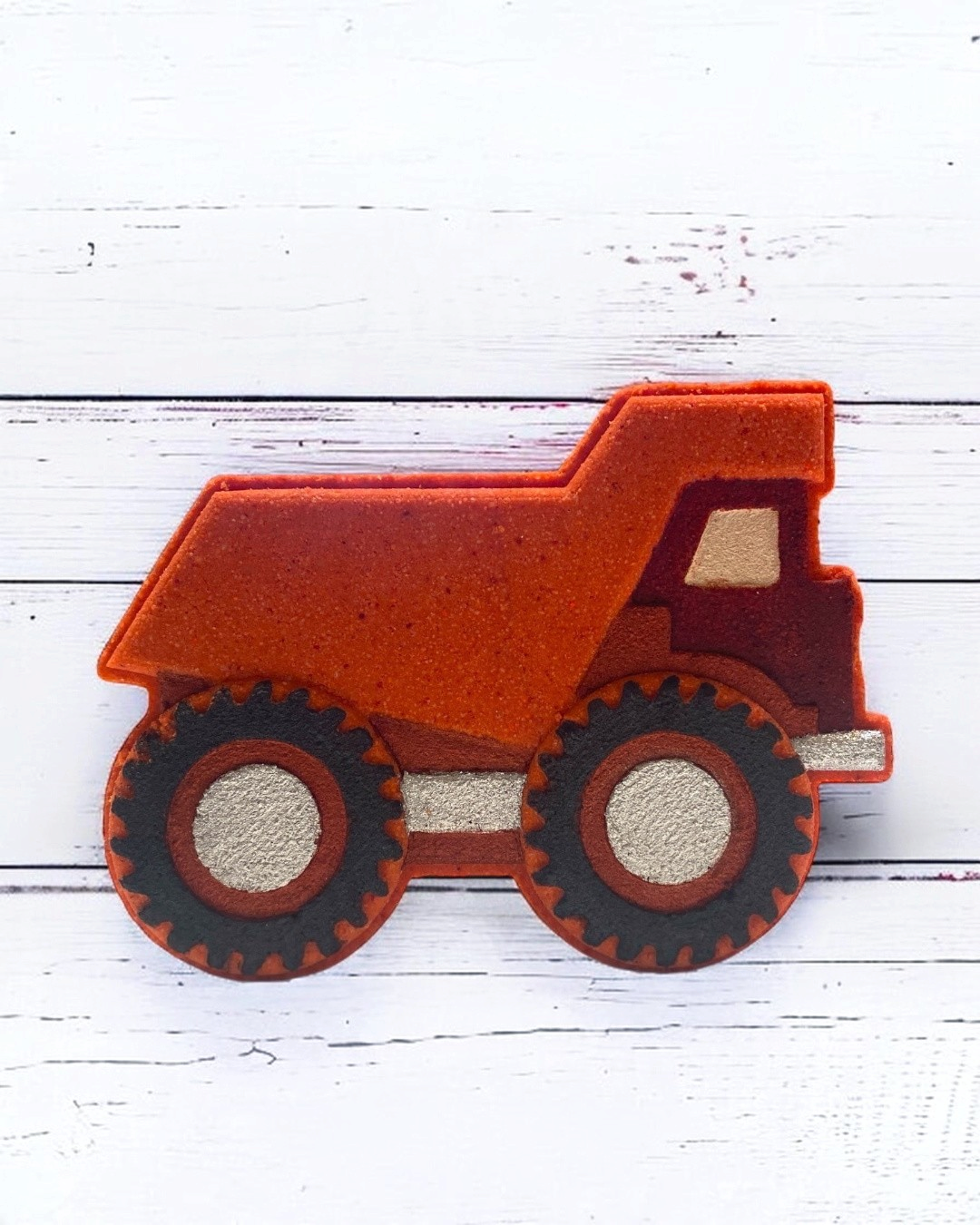 Red bath bomb dump truck on a white wooden surface