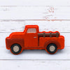 Red bath bomb truck with a wooden bed on a white wooden surface