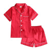 Red satin pajama set with white piping on a white background