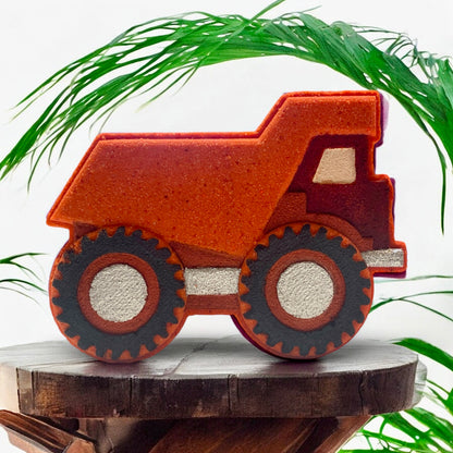 Bath Bomb dump truck on a wooden surface with green leaves in the background