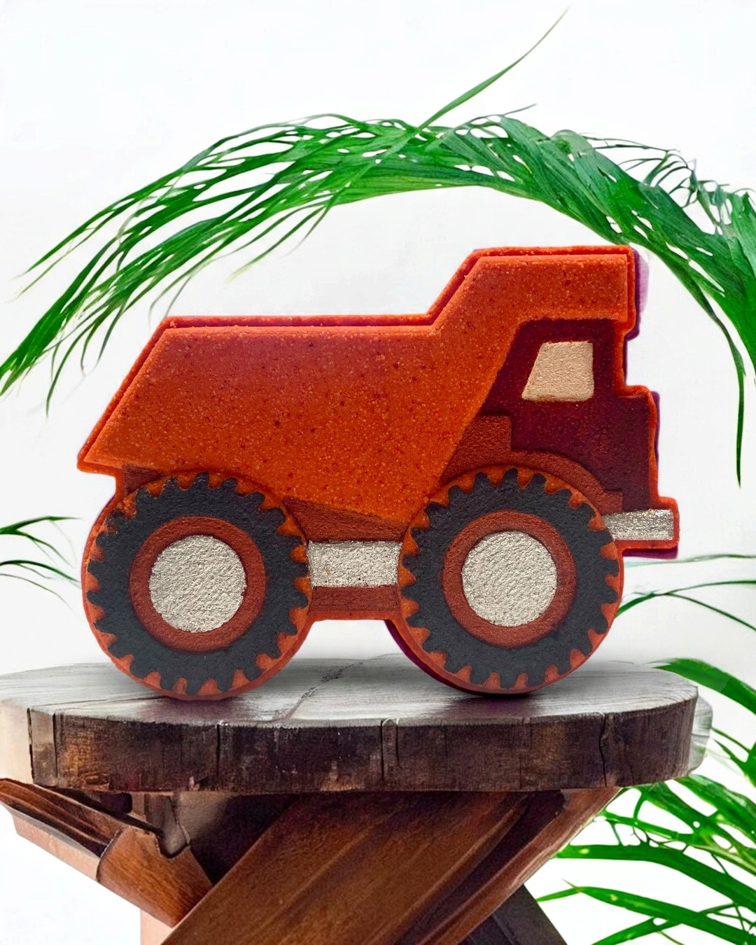Bath Bomb dump truck on a wooden surface with green leaves in the background