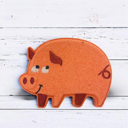 Felt pig-shaped object with a smiley face on a white wooden background