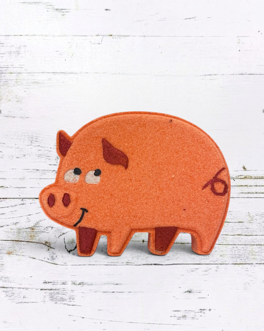 Felt pig-shaped object with a smiley face on a white wooden background